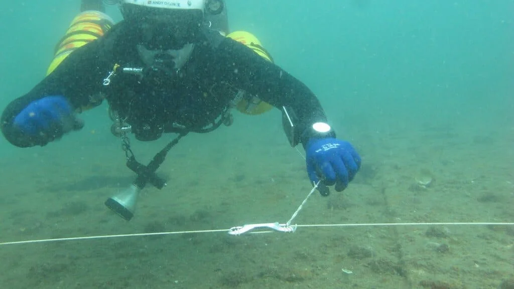 Advanced wreck diver demonstrates a safety spool tie off whilst searching for a lost diver